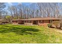 Expansive ranch-style home showcasing a brick and stone facade, a spacious lawn, and inviting red shutters at 220 Gregory Rd, Salisbury, NC 28147
