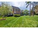 Well-manicured front yard of a brick home with lush green grass and mature trees at 7700 Red Oak Ln, Charlotte, NC 28226