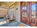 Inviting front porch with stone flooring, wood door, seating, and brick accents at 820 Cooks Cove Rdg, Lake Wylie, SC 29710