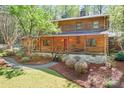 Charming log home featuring a covered porch, stone foundation, and landscaped yard at 1007 Mistywood Ln, Concord, NC 28027