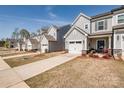 Street view of townhomes with light gray siding, attached garages, and manicured lawns on a sunny day at 11120 Pagebrook Ln, Charlotte, NC 28214