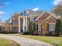A stately brick home with columns and professional landscaping, a circular driveway leading to the entrance at 1511 Churchill Downs Dr, Waxhaw, NC 28173