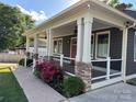 Inviting covered front porch with white pillars and stone accents with views of a well-manicured lawn at 232 Cromer St, Charlotte, NC 28208