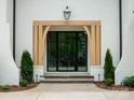Close-up of the home's grand entrance with stone steps, a wooden frame, and black framed glass doors at 3212 Willow Oak Rd, Charlotte, NC 28209