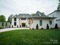 New construction home boasting a white brick facade, gray roof, manicured lawn, and wooden-framed entryway at 3212 Willow Oak Rd, Charlotte, NC 28209