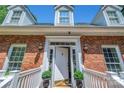 Close-up of the brick home's entry featuring a decorated front door with sconces and manicured potted plants at 3412 Country Club Dr, Gastonia, NC 28056