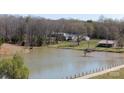 Scenic aerial view featuring a serene lake, a dock, surrounding trees, and well-maintained grassy areas at 4229 Motocross Trl, Edgemoor, SC 29712