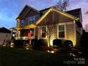 Beautiful two-story house with front porch and professional outdoor lighting at dusk at 7240 Baybrooke Ln, Harrisburg, NC 28075