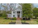 Classic white home boasts grand columns, a brick staircase, and lush greenery in the front yard at 8425 E Franklin St, Mount Pleasant, NC 28124