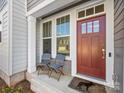 Inviting front porch featuring two blue chairs and a red front door at 1542 Cedar Tree Dr, Belmont, NC 28012