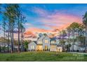 Stunning exterior of a modern farmhouse with a lush lawn and colorful sunset in the background at 6398 Chimney Bluff Rd, Lancaster, SC 29720
