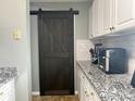 Kitchen featuring a modern barn door, granite countertops, and white cabinets with gold knobs at 3738 Ashley Hall Dr, Charlotte, NC 28227