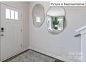Stylish entryway with modern mirrors, patterned rug, and white door creating a welcoming space at 2048 Harlequin Dr, Indian Trail, NC 28079