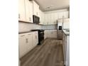 Modern kitchen with white cabinets, stainless steel appliances, hardwood floors and stylish backsplash at 313 Knotty Wood Dr # 79, Monroe, NC 28110