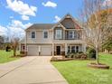 Charming two-story home featuring a well-manicured lawn, stone accents, and a welcoming front porch with a two car garage at 8137 Bryson Rd, Fort Mill, SC 29707