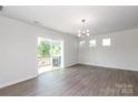 Bright living room featuring modern lighting, wood-look floors, and sliding glass door to outdoor balcony at 8232 Waxhaw Hwy, Waxhaw, NC 29173