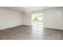 Spacious living area showcasing wood-look floors, contemporary light fixture, and sliding glass door to balcony at 8232 Waxhaw Hwy, Waxhaw, NC 29173