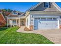 Inviting home featuring a welcoming front porch and attached two-car garage with stone accents at 229 River Birch Dr, Salisbury, NC 28146