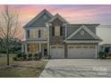 Inviting two-story home featuring a stone facade and a spacious three-car garage and manicured lawn at sunset at 276 Annatto Way, Tega Cay, SC 29708