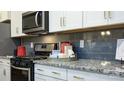 Stylish kitchen featuring gray subway tile backsplash, granite countertops, stainless appliances, and ample cabinet space at 7865 Iron Rd, Sherrills Ford, NC 28673