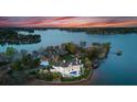 Aerial view of a lakeside estate featuring a private pool, boat dock, and meticulously landscaped grounds on the peninsula at 8228 Bay Pointe Dr, Denver, NC 28037