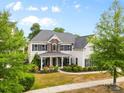 Two-story home featuring stone accents, a covered porch with seating, mature trees, and a well-manicured lawn at 11523 Warfield Ave, Huntersville, NC 28078
