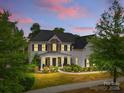 Beautiful two-story home featuring stone accents, covered porch, manicured landscaping, and walkway lighting at twilight at 11523 Warfield Ave, Huntersville, NC 28078