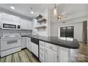 Close up of a modern kitchen with white cabinets, black countertops, subway tile backsplash, and stainless steel sink at 211 Heritage Blvd # 301, Fort Mill, SC 29715