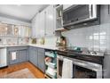 Well-lit kitchen featuring white cabinets, modern appliances, tile backsplash, and hardwood floors at 3407 14Th Sw Ave, Hickory, NC 28602