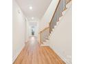 Bright hallway with hardwood floors leading to an outdoor view and a staircase with black metal spindles at 163 Windy Dell Dr, Tega Cay, SC 29708