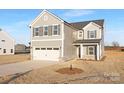 Two-story home featuring a two-car garage, gray siding, and a stone accent base in a spacious yard at 32586 Millingport Rd # 7147, New London, NC 28127