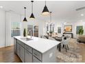 Open-concept kitchen featuring an island with a sink, gray cabinets, and pendant lighting with a dining area at 32586 Millingport Rd # 7147, New London, NC 28127