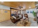 Cozy living room featuring wood ceiling, brick fireplace, and open access to the kitchen at 938 Pinehaven Dr, New London, NC 28127