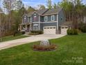 Traditional home showcasing a well-manicured lawn, stone accents, and a spacious driveway leading to a three-car garage at 1041 Crofton Dr, Waxhaw, NC 28173