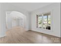 Bright living room featuring hardwood floors, large windows, and elegant archways at 15009 Lisha Ln, Charlotte, NC 28277