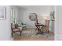 Brightly lit office space with hardwood flooring, round mirror, lamp, writing desk and two chairs at 15009 Lisha Ln, Charlotte, NC 28277