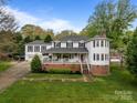 Charming two-story home with a brick foundation, white siding, covered front porch, and a separate two-car garage at 16421 Breckshire Dr, Huntersville, NC 28078