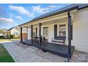 Inviting covered front porch featuring a cozy seating area, dark posts, and classic black shutters at 48 Mandalay Sw Pl, Concord, NC 28027