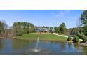 Picturesque view of estate home on green hill reflected in serene pond with fountain feature at 525 Lake Lynn Rd, Concord, NC 28025