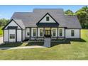 Exterior view of a charming modern farmhouse featuring white siding, black trim, and a spacious front lawn at 7419 Tesh Rd, Monroe, NC 28110