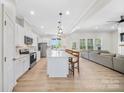 Spacious open-concept kitchen with white cabinets, island seating, and stainless steel appliances flowing into the living area at 7419 Tesh Rd, Monroe, NC 28110