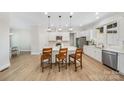 Bright kitchen featuring white cabinets, an island with seating, stainless steel appliances, and light wood flooring at 7419 Tesh Rd, Monroe, NC 28110