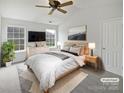 Inviting primary bedroom features a ceiling fan and ample natural light from the windows at 10827 Azure Valley Pl, Charlotte, NC 28269