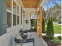Covered porch featuring comfortable seating, wood columns, and a view of the landscaped front yard at 215 Wyanoke Ave, Charlotte, NC 28205