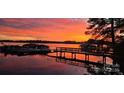 Waterfront home featuring a dock and boat slips with vibrant sunset views over the lake at 2587 Penngate Dr, Sherrills Ford, NC 28673
