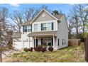 Two story home featuring light siding, blue shutters, a two-car garage and well-maintained landscaping at 4006 Stockbrook Dr, Charlotte, NC 28215