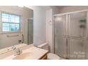Bright bathroom featuring a sliding glass door shower, vanity, and a window for natural light at 5700 Carmel Station Ave, Charlotte, NC 28226