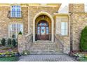 Elegant stone facade with arched entryway and wooden front door adorned with a wreath at 7295 Three Sisters Ln, Concord, NC 28027
