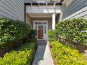 Inviting front entrance with a wood door framed by manicured shrubs and a white column portico at 8015 Greenview Terrace Ct, Charlotte, NC 28277
