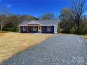 A cozy home featuring blue siding, a welcoming entryway, and a spacious gravel driveway under a clear blue sky at 237 Anson Ave, Norwood, NC 28128